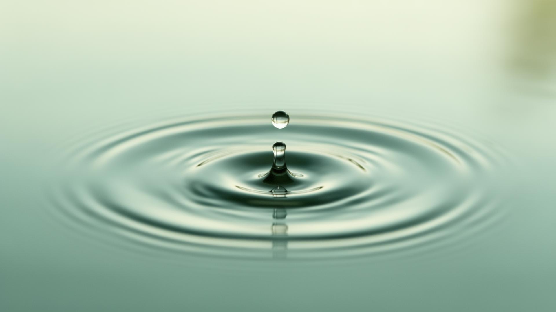 A single drop of water creating ripples on a still surface